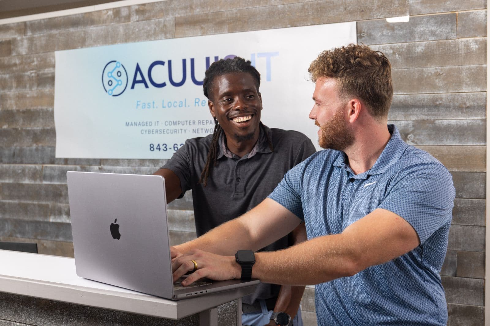 Two people discussing a laptop at the Acuuis office