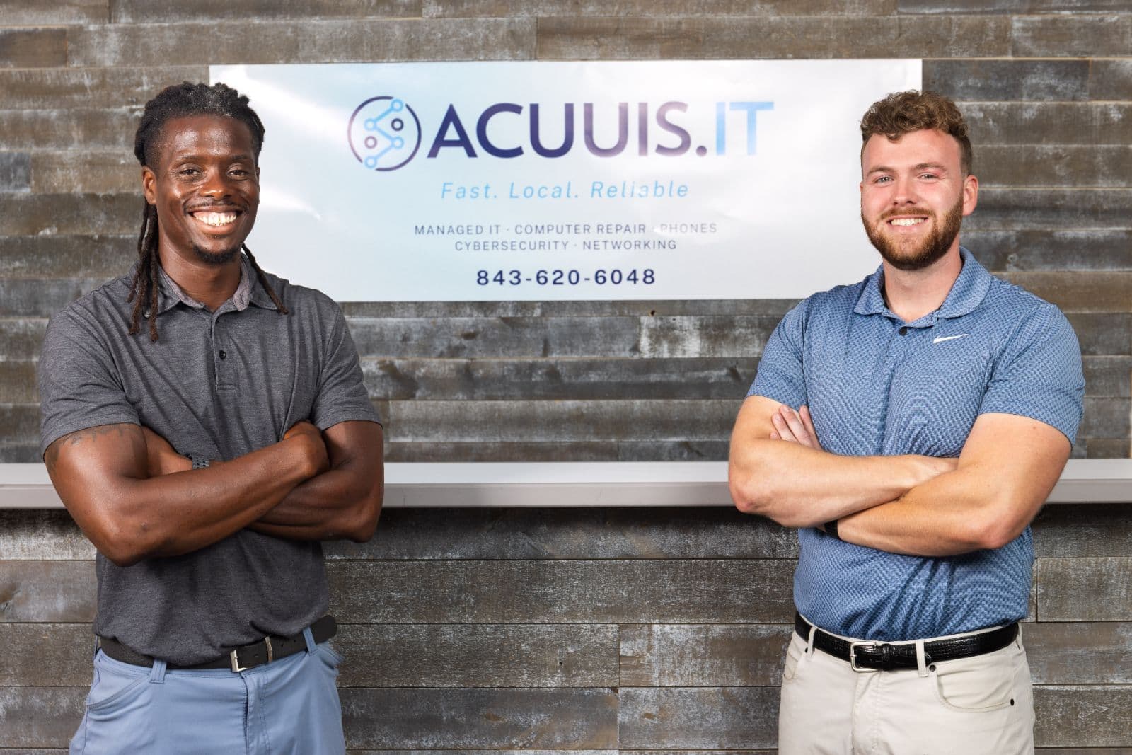 Two people beside the Acuuis IT office sign